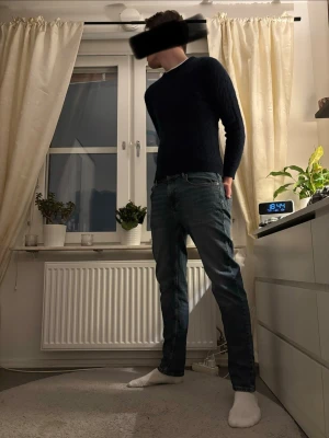 Mörkblå stickad tröja herr - Säljer en enkel och stilren mörkblå stickad tröja med rund hals. Tröjan har långa ärmar och en smal passform som sitter snyggt på kroppen. Perfekt till jeans eller chinos för en clean look.