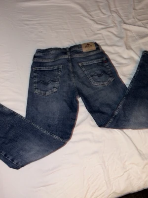 Blå Replay jeans, 10a - Säljer ett par klassiska blå jeans från Replay med raka ben och snygga detaljer på bakfickorna. Jeansen har normal passform och är tillverkade i slitstarkt denimtyg. Perfekta till vardags och funkar till det mesta i garderoben.