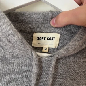  Soft Goat kashmirhoodie - Mysig grå hoodie från Soft Goat i 100% kashmir. Tröjan har huva med snörning och långa ärmar, perfekt för dig som gillar en stilren och avslappnad look. Ribbstickade muddar vid ärmslut och nederkant ger en snygg finish. Jag är 182 70kg på bilden