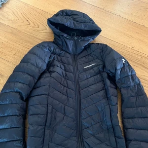 Svart dunjacka från Peak Performance - Säljer en svart dunjacka från Peak Performance med huva, snöret på dragkedjan har lossnat som ni ser på andra bilden men funkar bra ändå💕