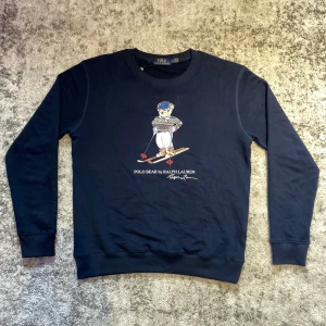 Ralph lauren Polo bear tröja - Säljer denna riktigt schyssta Ralph lauren tröjan med den ikoniska Polo bear bilden mitt på. Nytt skick, bekvämt material, perfekt för kallare dagar.                                           ⚜️Gratis armband vid köp av detta plagg. Välj mellan ett Anchor eller cuff armband, annars medföljer ett slumpmässigt⚜️