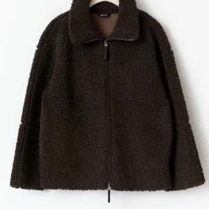 Mörkbrun teddyjacka med dragkedja - Mysig mörkbrun teddyjacka med hög krage och hel dragkedja framtill.  Helt ny med prislapp. 