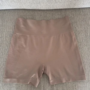 Bruna seamless träningsshorts Primark - Säljer ett par bruna seamless träningsshorts från Primark WORKOUT. De är högmidjade med bred resår och har en tight passform. Materialet är stretchigt och består av polyester och elastan, perfekt för gym eller yoga.