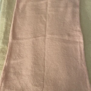 Ljusrosa stickad långkjol - Mysig och enkel ljusrosa långkjol i stickat material. Kjolen har rak passform och är perfekt för dig som gillar en stilren och soft look. Passar snyggt med en oversized tröja eller en tight topp.