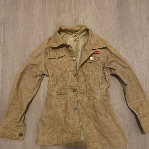 Beige manchesterjacka från Exit - Säljer en beige manchesterjacka från Exit med klassisk krage, knappar framtill och fickor på bröstet. 