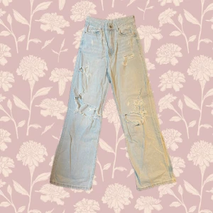 Ljusblå ripped jeans från Bershka - Ljusblå jeans från Bershka med hög midja och raka, vida ben. Snygga slitningar och hål framtill ger en cool, perfekt för dig som gillar streetstyle. Tveka inte att höra av dig vid frågor!  