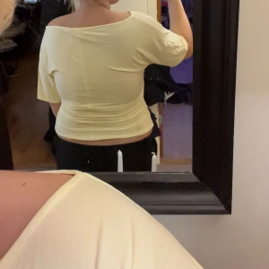 Ljusgul offshoulder topp - Säljer en ljusgul topp med offshoulder-design och korta ärmar. Toppen är figurnära och har en mjuk, stretchig känsla. Perfekt för dig som gillar en enkel men snygg look med lite extra edge. Passar dig som vill ha en topp som sitter tight och framhäver axlarna.