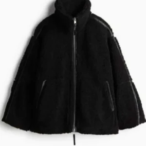 Svart teddyjacka med dragkedja - Mysig svart teddyjacka med hög krage och hel dragkedja framtill. Jackan har två sidofickor och en loose passform som ger en chill vibe. Perfekt för kalla dagar när du vill vara både varm och snygg.