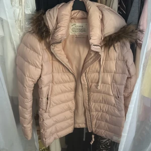 Ljusrosa pufferjacka Odd Molly - Säljer en ljusrosa pufferjacka från Odd Molly med huva och fuskpälsdetalj. Jackan har dragkedja framtill, två fickor med dragkedja och snyggt broderad Odd Molly-logga på ärmen. Perfekt för kalla dagar och riktigt mysig att bära.