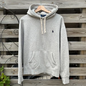 Ralph Lauren Grå Hoodie - Supersnygg hoodie från Ralph Lauren. Storlek M, skulle säga att den passar S Tröjan är i ett fint skick, enda ”defekten” är en minimal färgförändring på sista bilden som inte syns så mycket irl (som ni kan se i bilden), ses även på mitten av tröjan i första bilden. Väldigt mjuk och härlig, inte använd mycket alls. Be gärna om mått. Hör gärna av er vid funderingar🙌🏻🙌🏻