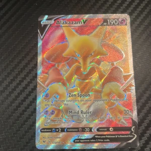 Alakazam V - Coolt och glittrande Pokémonkort med Alakazam V! Perfekt för samlare och fans som vill boosta sin lek med en kraftfull och snygg karaktär. Kortet har unika attacker som Zen Spoon och Mind Ruler. Ett måste för dig som älskar Pokémon!