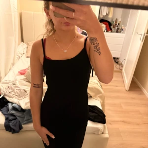 Svart klänning med öppen rygg och snörning - Säljer en svart, tight klänning med smala axelband och snygg öppen rygg med snörningsdetaljer. Klänningen har en enkel och stilren look som passar perfekt när du vill känna dig extra snygg. Materialet känns mjukt och följsamt mot kroppen.