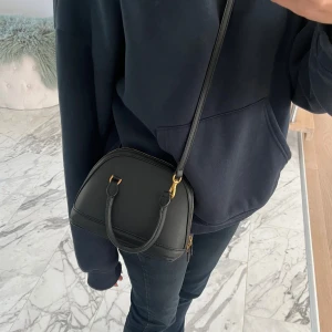 Svart axelväska  - Snygg svart axelväska, knappt använd o är i superfint skick. Gulddetaljer och med justerbart band