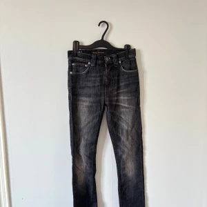 Svarta slim jeans från Nudie Jeans - Snygga svarta jeans från Nudie Jeans med slitna detaljer och tvättad look. Klassisk femficksmodell med smal passform och raka ben. 