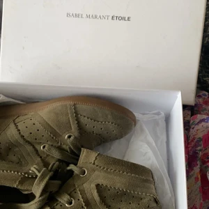 Isabel Marant Étoile mockasneakers khaki - Säljer ett par khakigröna från Isabel Marant Étoile i mjuk mocka med perforerade detaljer och snörning. Skorna har en platt gummisula i brunt och en diskret kilklack för extra höjd. Bra skick, sällan använda 💗