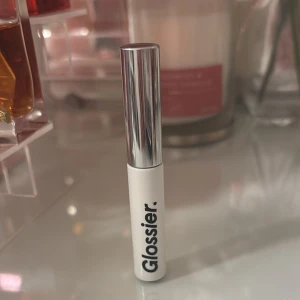 Glossier Boy Brow ögonbrynsgel - Glossier Boy Brow ögonbrynsgel i vit tub med silvrigt lock. Perfekt för att forma och styla brynen med en naturlig finish. Smidig applikator och stilren design, passar dig som vill ha snygga och definierade ögonbryn.