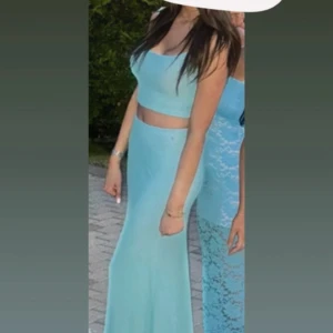 Ljusblå långklänning med crop top - Supersnygg ljusblå långklänning i tvådelad modell med croppad topp och figurnära kjol. Klänningen har ärmlös design och en stilren, enkel look som verkligen sticker ut. Perfekt för dig som vill ha något unikt och trendigt till speciella tillfällen.