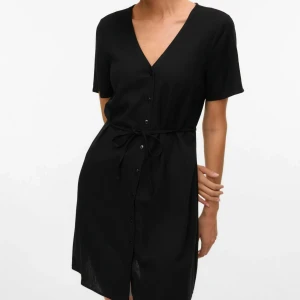 Svart kort klänning från H&M Divided - Säljer en helt ny svart klänning från H&M i storlek S. Klänningen har knappar framtill, ett tunt band vid midjan som man knyter, v-ringning och T-shirt ärmar. Den är sval och perfekt för varma dagar. Kommer med prislappen kvar.  Vänligen läs min bio innan du gör ett köp; där hittar du bland annat information om leveransprocessen med mera 😊   #kläder #H&M #klänning #sommar