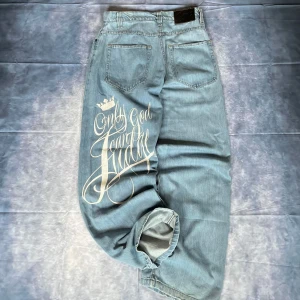 Y2K BSAT Baggy Jeans - 🔥 Early 2000s BSAT denim with iconic “Only God Can Judge Me” back print. Light blue wash, oversized baggy fit with wide legs – perfect for Y2K streetwear and hip-hop inspired looks.  W33/L32   📏 Measurements (in cm):  Waist: 42  Hips: 46 Back Rise: 37 Thigh: 36.5 Leg Opening: 25.5 Inseam: 82 Outseam: 109.5  Condition: No flaws, Great vintage condition, 100% wearable.  #Y2KJeans #BaggyDenim #BSATJeans #Streetwear2000s #Y2KStreetwear #OnlyGodCanJudgeMe #VintageDenim #Y2KStyle