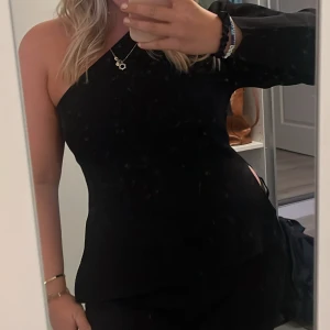 Svart oneshoulder topp med lång ärm - Snygg svart topp med oneshoulder och en liten slits på sidan, säljs då den inte används längre💕🥰Använd max 2 gånger!