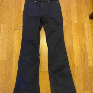 Svarta bootcut jeans från H&M, strl 38 - Svarta jeans från H&M i storlek 38 med klassisk femficksdesign. Byxorna har bootcut-modell med utsvängda ben och normal passform. Tillverkade i bomullsmix för en bekväm känsla och snygg siluett.