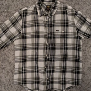 Rutig skjorta från Lee i svart och grå/grön - Snygg rutig skjorta från Lee i svart, grått och vitt. Regular fit med klassisk krage, bröstficka och vita knappar framtill. 