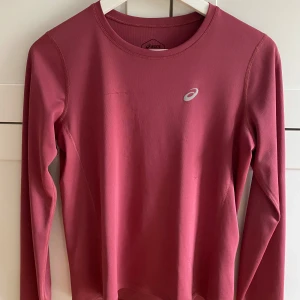 Vinröd långärmad träningströja Asics - Säljer en vinröd långärmad träningströja från Asics, perfekt för löpning eller gym. En söm som gått upp lite, se sista bilden!