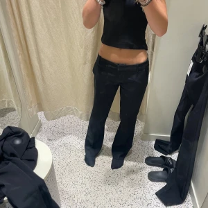 Svarta kostymbyxor - Snygga svarta kostymbyxor med bootcut-snitt och låg midja. Byxorna har klassiska fickor och bälteshällor, perfekta för en stilren look. Passformen är normal och materialet känns mjukt och följsamt. Från bikbok. Helt nya utan prislapp. Nypris:500kr