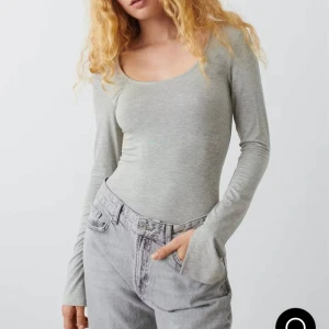 Ljusgrå långärmad topp med rund hals - Säljer en stilren ljusgrå långärmad topp med rundad halsringning. Toppen är figurnära och har en enkel, clean look som passar perfekt till jeans eller kjol. Tillverkad i mjukt och stretchigt material för en bekväm passform. Med slits i armarna.