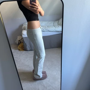 Ljusgrå mjukisbyxor med snörning - Superbekväma ljusgrå mjukisbyxor med bred resår i midjan och snörning framtill. Byxorna är i en bootcut modell och är gjorda i mjukt bomullsmaterial, perfekta för chill dagar hemma eller när du vill vara extra comfy. De har väldigt låg midja och jag säljer de pågrund av att dom har blivit lite för korta för mig. Hade varit perfekta om det vore en bra längd för mig.