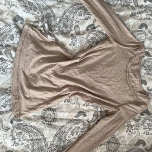 Beige långärmad topp från Cubus - En basic beige långärmad topp från Cubus i mjuk bomullsmix. Modellen har rund halsringning och en figurnära passform som funkar till allt. Perfekt att styla med jeans eller kjol för en enkel och clean look.