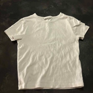 Vit basic t-shirt i bomull - Enkel och stilren vit t-shirt i mjuk bomull. Klassisk rund halsringning och korta ärmar, perfekt att matcha med jeans eller shorts. Snygg och clean look som funkar till det mesta.