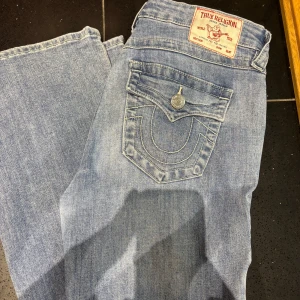 True Religion Becca Bootcut Jeans - Säljer ett par klassiska blå jeans från True Religion, köpte 1 månad sen modell Becca med bootcut passform och snygga detaljerade bakfickor med knappar.