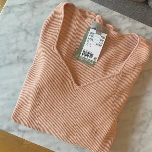 Korallfärgad ribbad långärmad tröja H&M - Supersnygg ribbad tröja från H&M med v-ringad hals och lång ärm. Stretchigt material i storlek S.