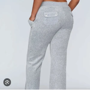 Grå mjukisbyxor med snörning - Snygga grå mjukisbyxor med raka ben och bred resår i midjan. Byxorna har snörning framtill, stora fickor fram och bakfickor med lock och knappdetalj. Perfekta för en chill och avslappnad look.