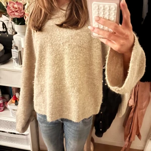 Beige stickad hoodie från Gina Tricot - Mysig beige stickad hoodie från Gina Tricot i oversized modell. Tröjan har långa ärmar med lite vidare passform och huva. Perfekt för höst och vinter när du vill ha något riktigt skönt och stilrent.
