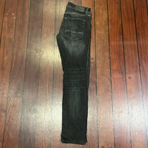 Svarta slim jeans Jack & Jones Glenn - Svarta slim fit jeans från Jack & Jones, modell Glenn. Jeansen har en snygg tvätt med lätt slitning och klassisk femficksdesign. Tillverkade i stretchigt jeanstyg för skön passform och stilren look.