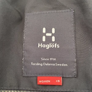 Svart Haglöfs skaljacka XS dam - Svart skaljacka från Haglöfs i dammodell, storlek XS. Jackan har huva, två stora bröstfickor med dragkedja och är tillverkad i slitstarkt material med GORE-TEX. Perfekt för utomhusaktiviteter och äventyr.