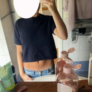 Mörkblå croppad stickad tröja - Säljer en mörkblå croppad stickad tröja med korta ärmar och rund hals. Tröjan har en enkel och stilren design som är perfekt till jeans eller kjol. Mjuk och skön att bära, passar dig som gillar en avslappnad men trendig look. Från Gina i storlek xs 