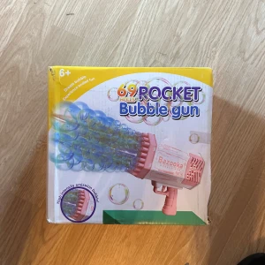 Rocket Bubble Gun 69 Holes Bazooka - Elektrisk bubbelpistol med 69 hål för maximal bubbeleffekt. Levereras i originalkartong med tillbehör och uppladdningsbart batteri. Produkten är i nyskick. 