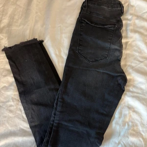 Svarta skinny jeans från Denim Rebel - Svarta skinny jeans från Denim Rebel med råa, fransiga benslut och klassisk femficksdesign. Jeansen har dragkedjegylf och är tillverkade i stretchigt denim för en tight passform. Perfekta för dig som gillar en modern och edgy look.
