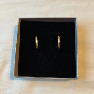 Guldiga chunky hoops örhängen från Guldfynd - Säljer ett par snygga chunky hoops i gulplätering. Kommer i en stilren ask. Aldrig använda, ny pris 600. Under pläteringen är det silver. 