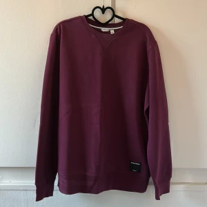 Vinröd sweatshirt från Björn Borg - Vinröd sweatshirt från Björn Borg med rund halsringning och diskret svart logolapp nertill. Tröjan har lång ärm och klassisk passform, perfekt för en chill och stilren look. Tillverkad i mjuk bomull för extra komfort.