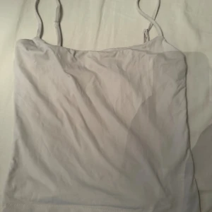 Ljusgrå linnetopp från Gina Tricot - Säljer en enkel och stilren ljusgrå linnetopp från Gina Tricot. Toppen har tunna, justerbara axelband och är tillverkad i ett mjukt och stretchigt material. Perfekt att matcha med jeans eller kjol för en clean look.