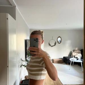Beige och vit randig croppad stickad topp - Superfin croppad topp med breda beige och vita ränder. Stickad i mjukt material med ribbade kanter vid hals, ärmslut och nederkant. Kortärmad och perfekt till jeans eller kjol för en chill look. Från H&M