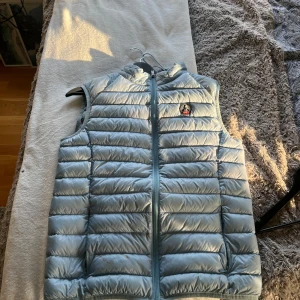  JOTT väst - Snygg ljusblå dunväst från JOTT med quiltad design och dragkedja framtill. Västen har en klassisk passform och är perfekt för lager-på-lager. Märkets ikoniska logga sitter på bröstet och materialet är lätt och smidigt. Nypris runt 1700