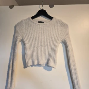 Vit croppad stickad tröja Shein - Supermjuk och fluffig vit stickad tröja från Shein. Croppad modell med ribbat mönster och långa ärmar. Den var används nån gång och har någon mörk fläck på framsidan, har inte tvättat den så vet ej om fläcken försvinner eller ej 