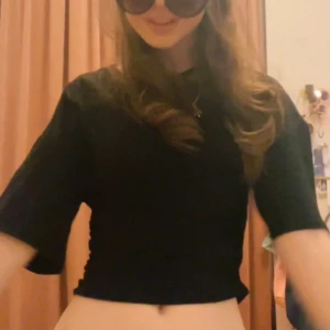 Svart figursydd T-shirt från Gina - En svart croppad topp med rund halsringning och halvärmar. Enkel och stilren design som passar till jeans eller kjol. Mjuk och stretchig känsla, perfekt för dig som gillar minimalistiska plagg. 