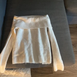 Offshoulder vit stickad tröja Gina Tricot - Superfin vit stickad offshoulder-tröja från Gina Tricot. Tröjan har bred ribbad kant upptill och långa ärmar. Perfekt till hösten då den är varm och gosig.