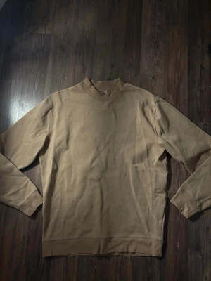 Beige sweatshirt från Zara - En stilren beige sweatshirt från Zara med rund halsringning och långa ärmar. Tröjan är i mjuk bomull och har en klassisk passform som funkar till många olika outfits. Perfekt för dig som gillar en enkel och clean look.